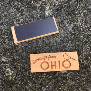 Wood Magnet with "Greetings from Ohio" and a cardinal outline laser design on a concrete background