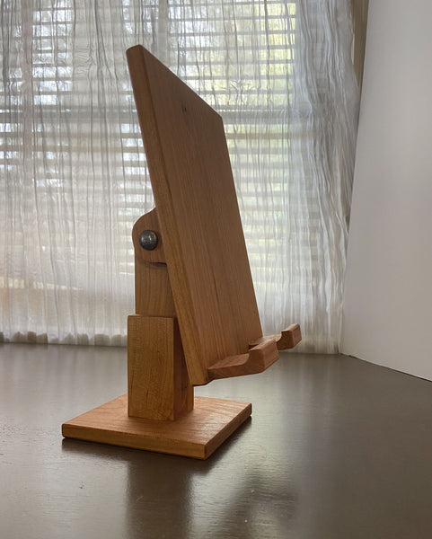 Wood adjustable tablet stand shown from the side. A sheer curtained window in the background.