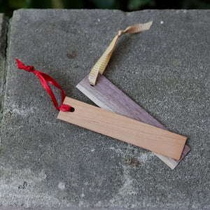 Two wood bookmarks with a ribbon tied on end on concrete