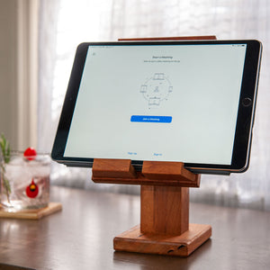 Adjustable handcrafted wood tablet stand with an iPad showing a Zoom Meeting. A cocktail glass on the side on a handmade wood coaster by Fallen Tree Woodshop.