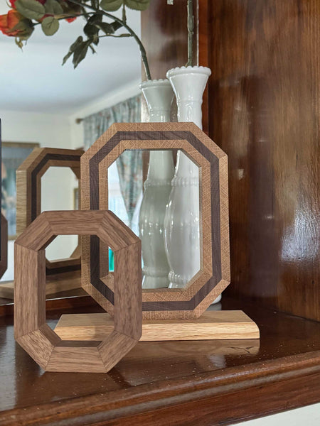 Wooden OSU Block O, two toned frame in front of  mirror on a wooden surface. Smaller solid wood Block O in front of larger Block O.