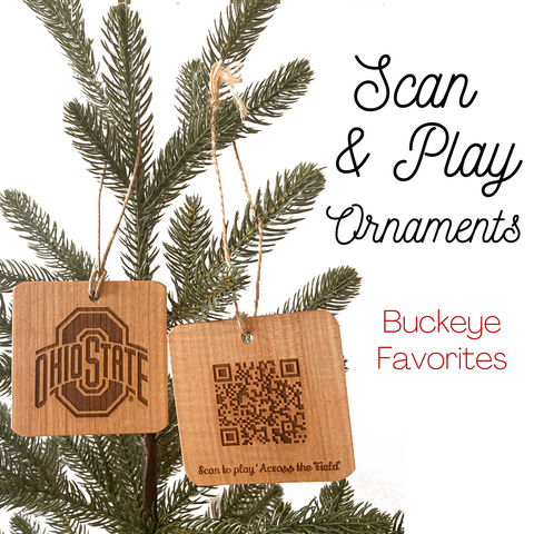 Two hand cut wood ornaments laser engraved OSU Sport logo design on one and and on the back a QR Code to play the song 'Across the Field.' Hanging from a pine tree with white background.