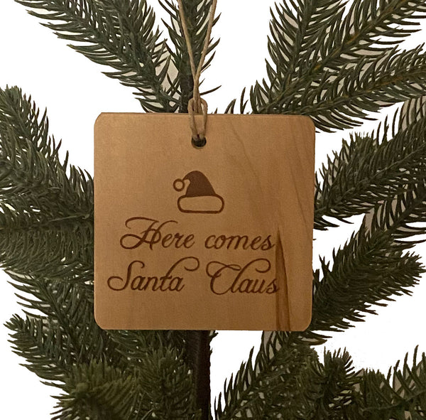 Hand crafted wood ornament with laser engraved designs handing on a small pine tree with a white background. Ornament on left has Deck the Halls design and Ornament on the right has a QR Code to be able to scan and play the song.