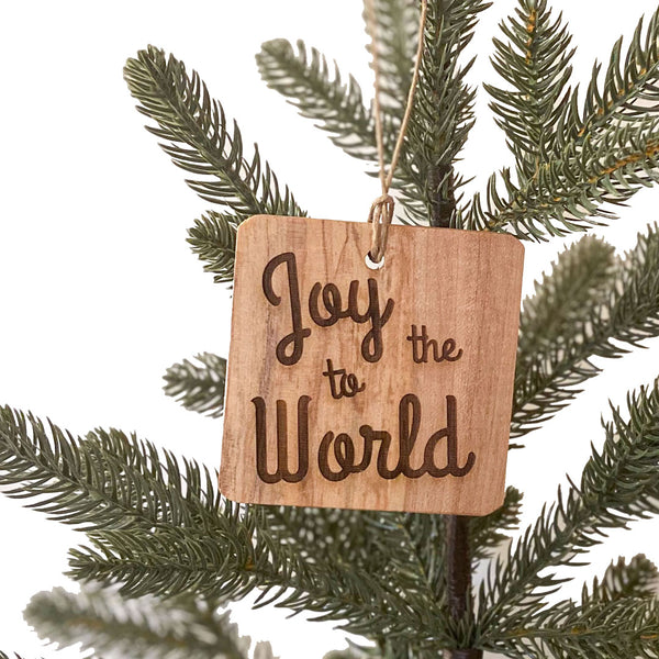 Hand cut wood ornament with Joy to the World laser engraved on a pine tree background