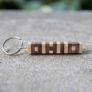 Hand cut letters Ohio keychain in walnut and ash wood. Concrete background.