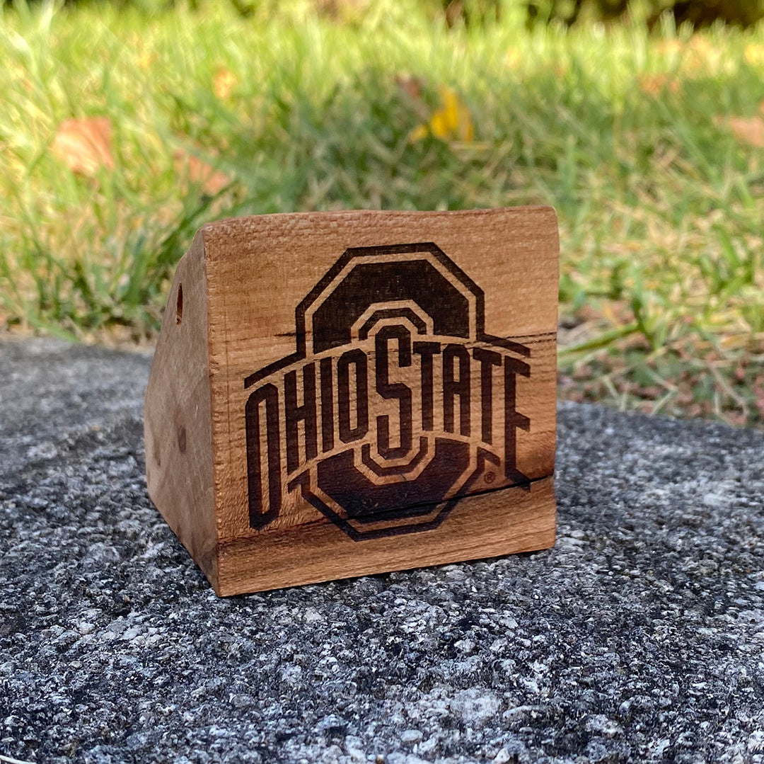 Small hand cut wood block with official The Ohio State University sport logo laser design on a grass background. Licensed by OSU gift.