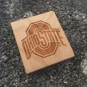 Ohio State sport logo wood magnet with a concrete background.