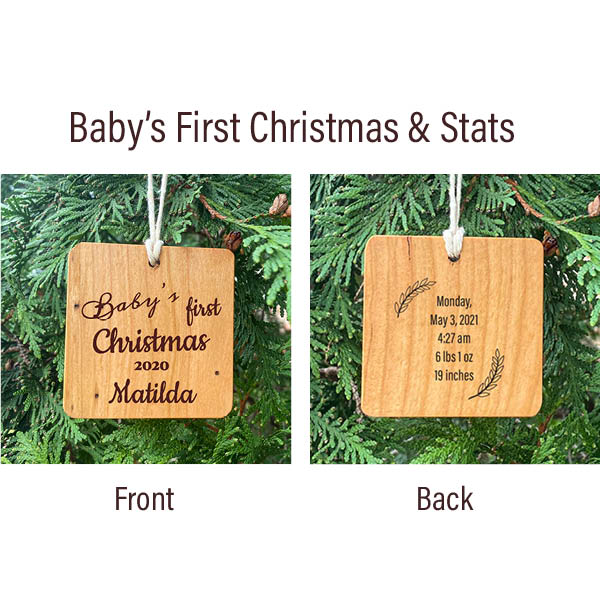 Baby's First Christmas & Stats wood ornament. Two ornaments hanging side by side on a pine tree, the front with Baby's first Christmas. The back laser engraved birth stats.