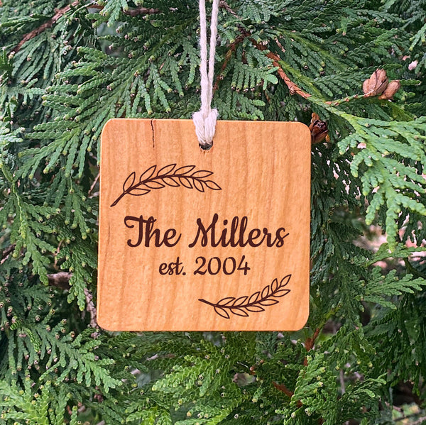 Wood Ornament laser engraved text The Millers est 2004 on pine tree background.