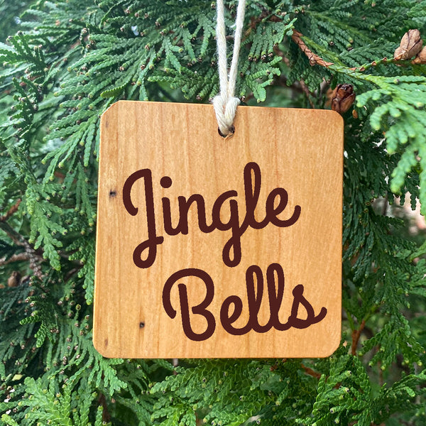Jingle Bells text on a wood cut ornament on a pie tree.