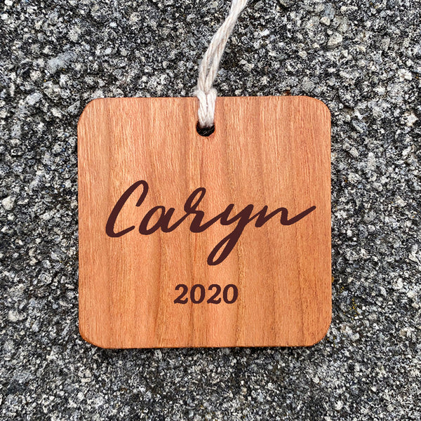 Wood ornament with Caryn 2020 on a concrete background.