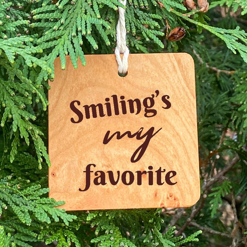 Smiling's my favorite ornament on pine tree background.