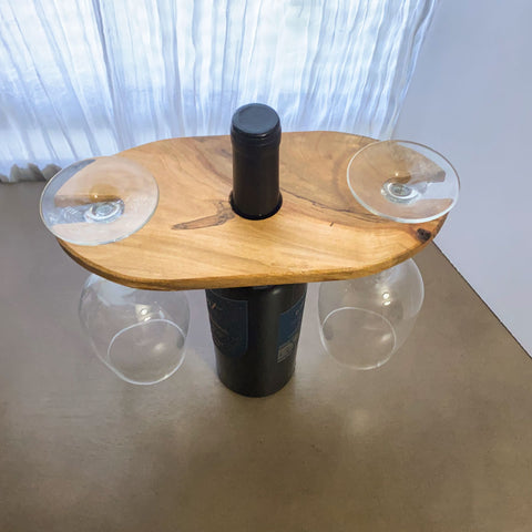 Wood wine and glass display, shown from an above angle with two glasses hanging from the display and a bottle in the center.