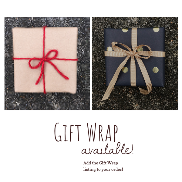 Two gift wrapped boxes side by side. One with Kraft paper and red yarn. The other with black paper and gold dots with a gold ribbon. The text 'Gift Wrap Available' Add the Gift Wrap listing to your order! Below in brown text on white background.