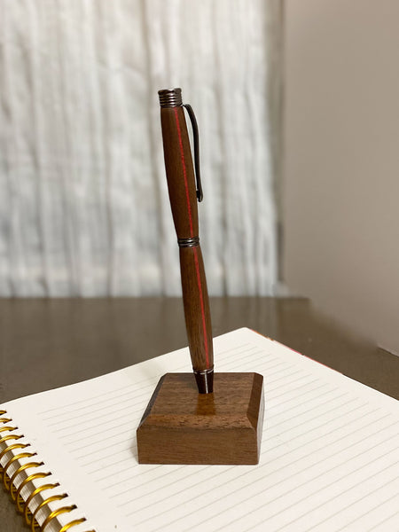 Walnut hand turned pen with a red stripe on a notebook.