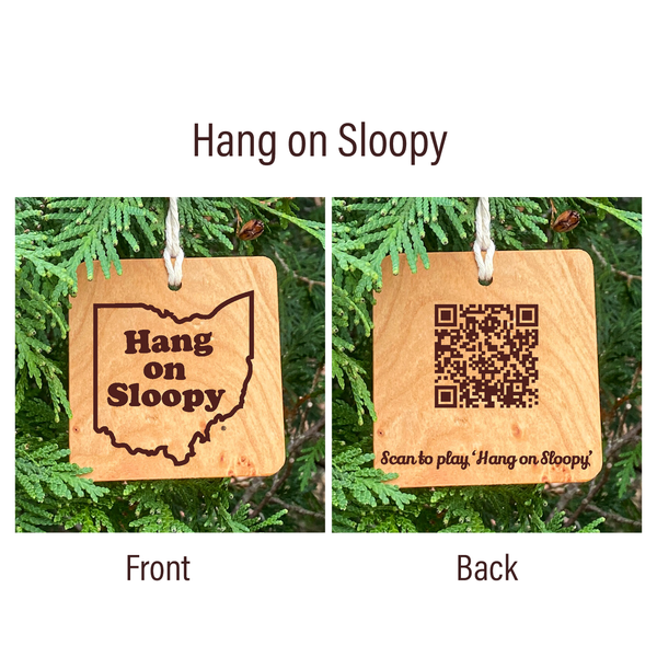 Hang on Sloopy wood ornament shown front and back. Front with Hang on Sloopy text in Ohio state outline, back with QR Code to play the song. Wood natural ornaments on pine tree background.