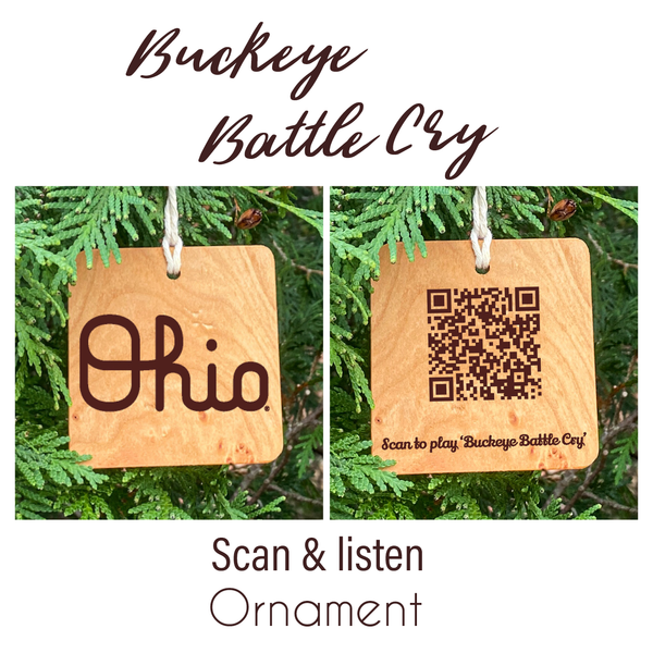 Natural wood ornament with laser engraved OSU Script Ohio. Next to it another ornament showing the back, laser engraved QR Code to scan and play 'Buckeye Battle Cry'. Hanging from lush pine trees. Photos are in a white background with the text Buckeye Battle Cry in script on top and below the photos the text 'Scan & listen Ornament'.