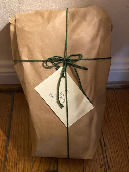 Odd shaped package wrapped in craft brown paper in green ribbon