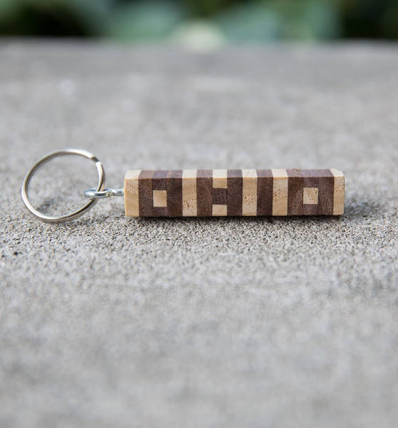 Hand cut letters Ohio keychain in walnut and ash wood. Concrete background.