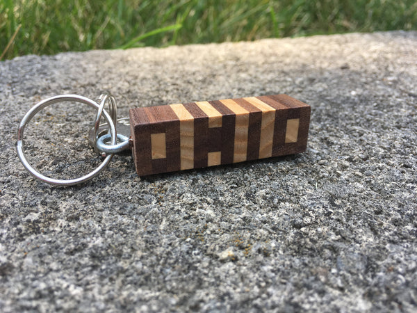Hand cut letters Ohio keychain in walnut and ash wood. Concrete background.