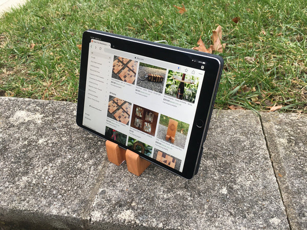 Hand crafted phone stand from fallen cherry, set with a grass background.Shown with an iPad on the stands.