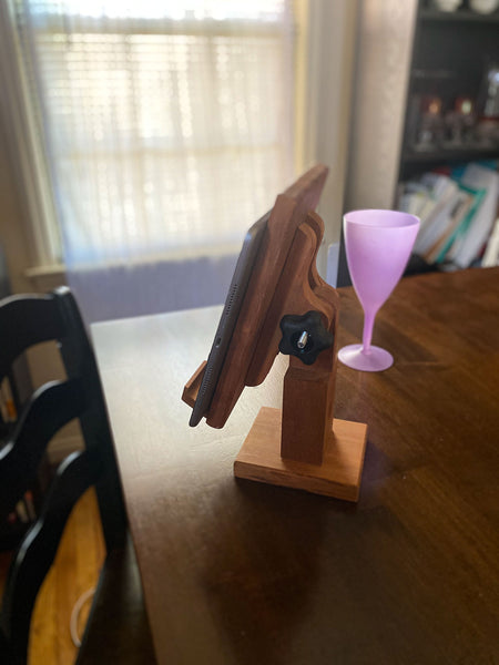 Adjustable  hand made wood tablet stand on a dinning room table with a vintage purple wine glass in the back.
