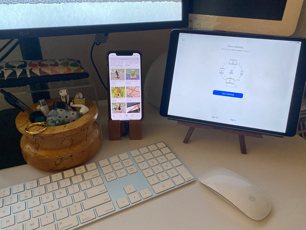 Easel phone stand with an iPad on the right and block phone stand with a phone on the left. A mouse and keyboard in the forground.